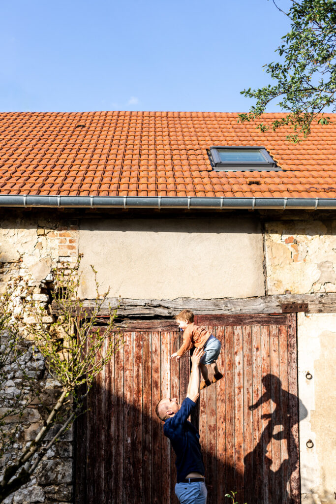 photo de papa qui lance son fils en l air dans le jardin par camille piovesan photographe fontainebleau