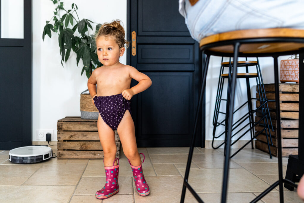 petite fille en culotte et bottes de pluie pendant un reportage du quotidien avec camille piovesan