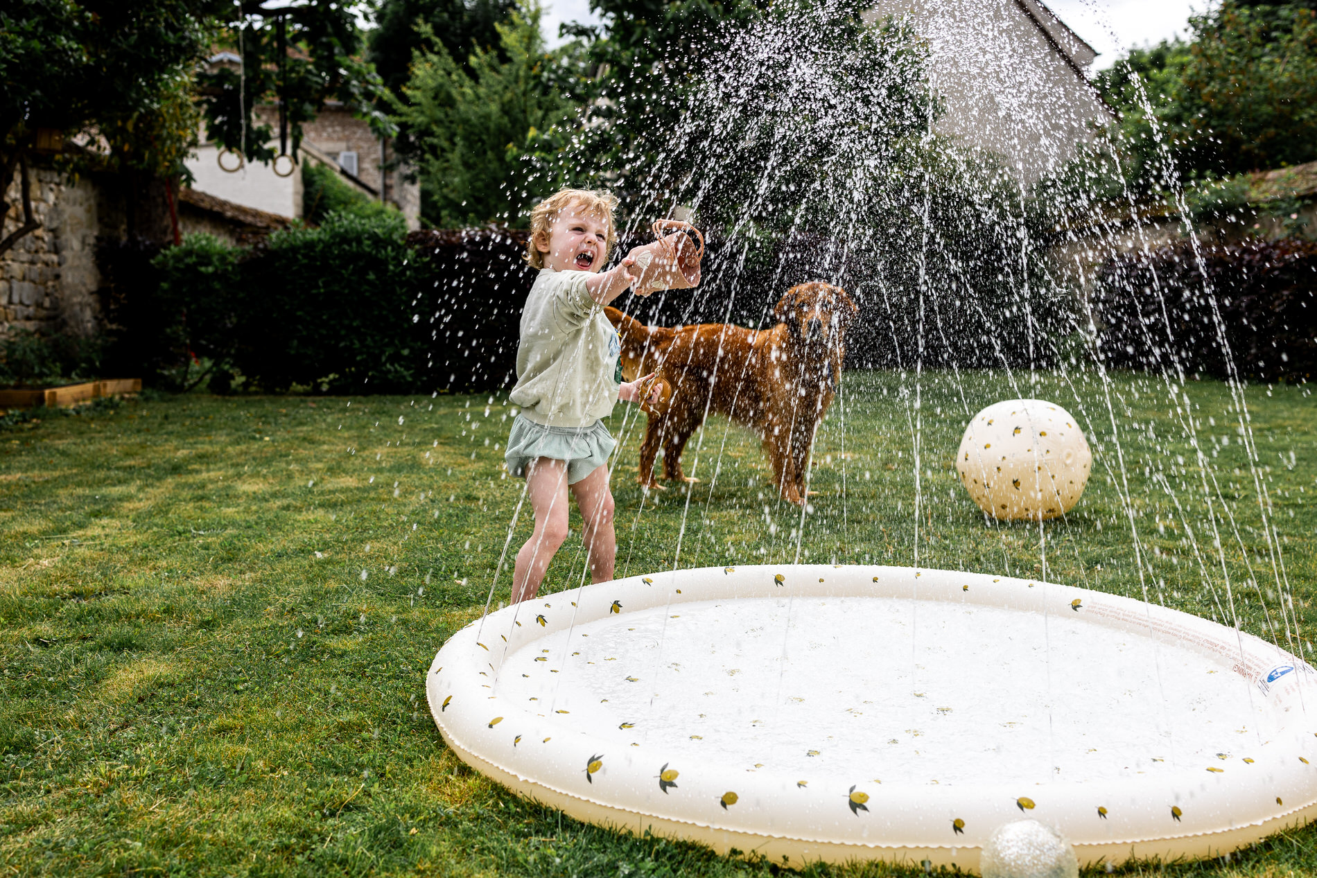 enfant jouant dans le jardin avec une piscine et de l'eau lors du shooting photo