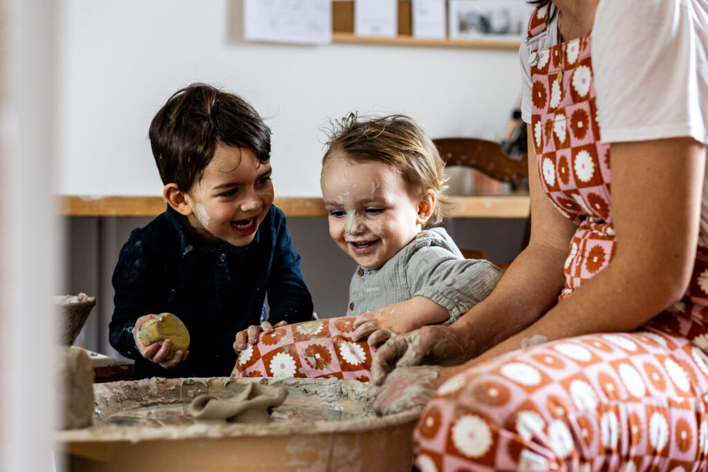 deux enfants jouent dans un atelier de ceramique de leur maman pendant un reportage photo famille a fontainebleau