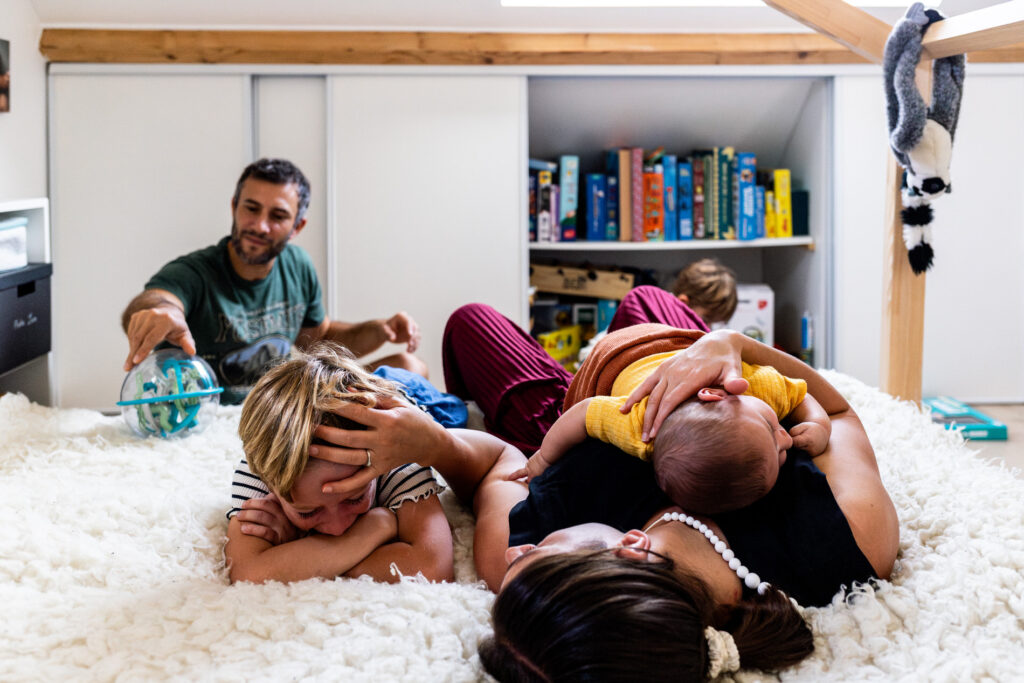 une famille avec trois petits garcon dans une chambre la maman reconforte un de ses fils qui pleure pendant une seance photo famille avec camille piovesan