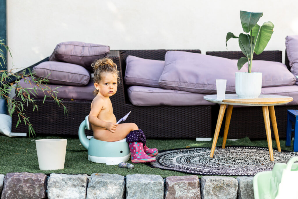 une petite fille sur son pot pendant une seance photo famille avec camille piovesan a fontainebleau