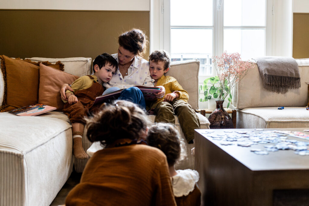 une maman et ses enfants en train de lire une histoire dans le salon pendant un reportage photo famille avec Camille Piovesan
