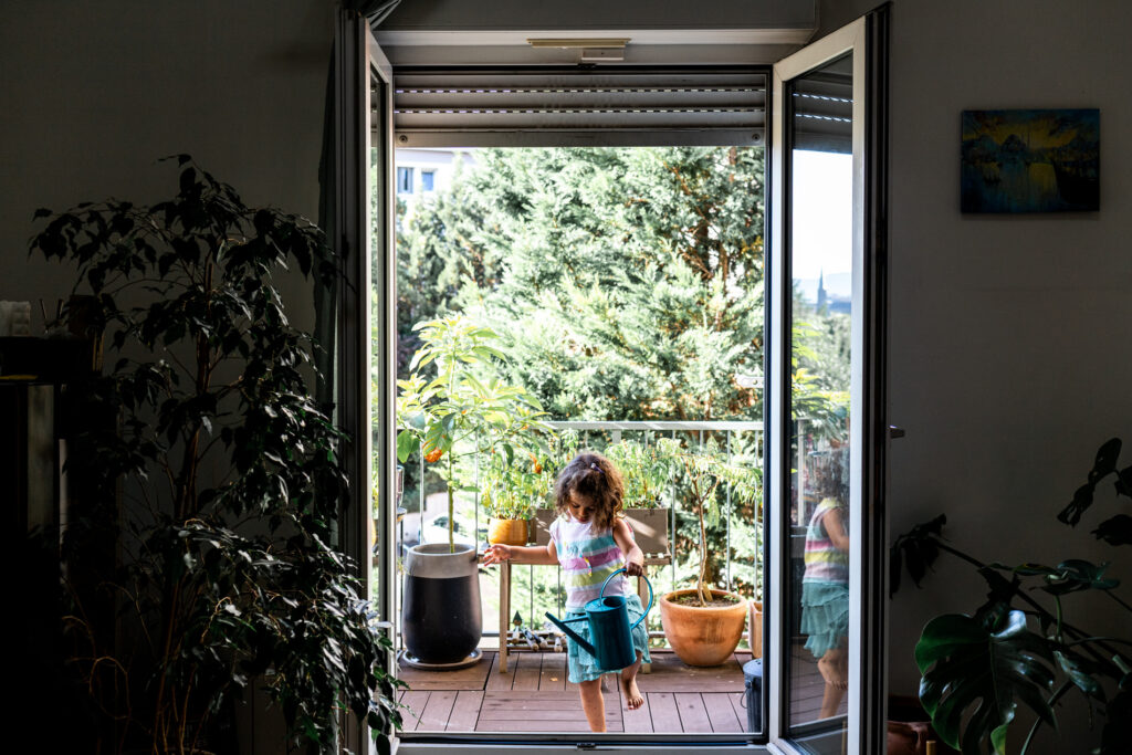 petite fille arrosant les plantes pendant un reportage photo famille avec Camille Piovesan