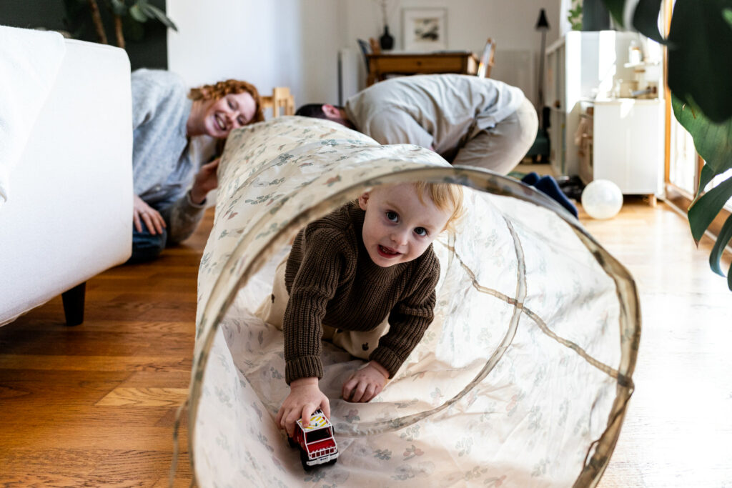 petit garcon jouant dans le salon avec ses parents pendant un reportage photo famille a Fontainebleau