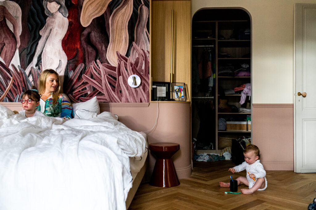 petite fille jouant a cote du lit de ses parents avec sa maman qui la regarde lors du reportage photo famille bordeaux