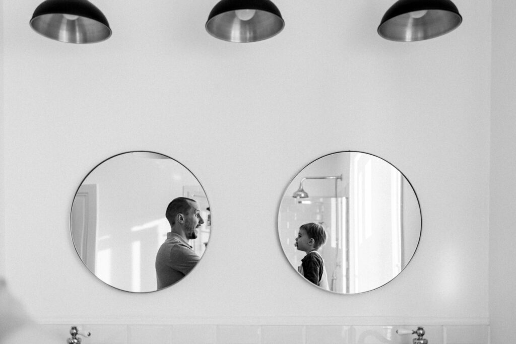 un papa et son fils dans les reflets de deux miroir pendant un reportage photo famille a fontainebleau